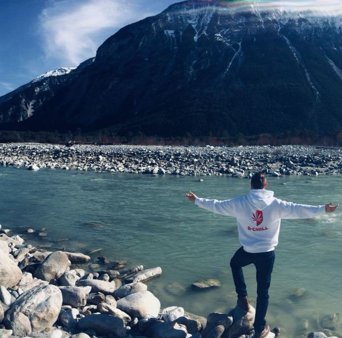 man with open arms in front of river and mountains