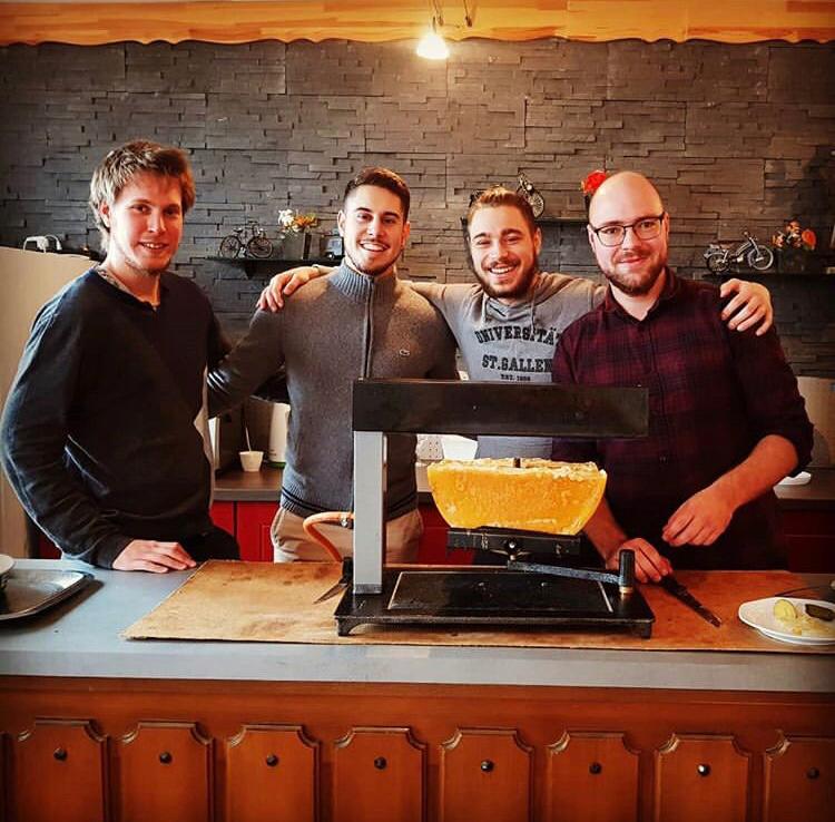 four guys behind a raclette oven
